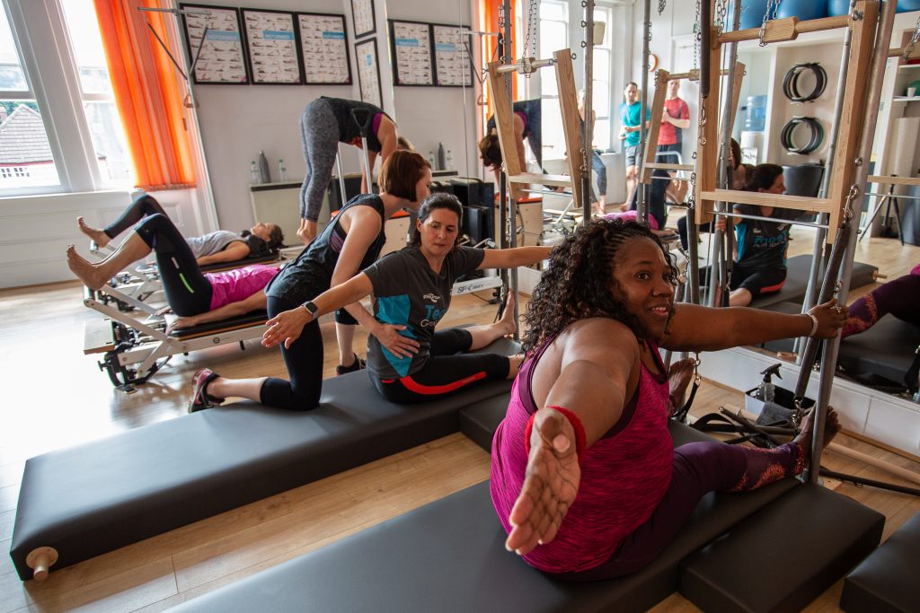 men and women on apparatus doing Pilates