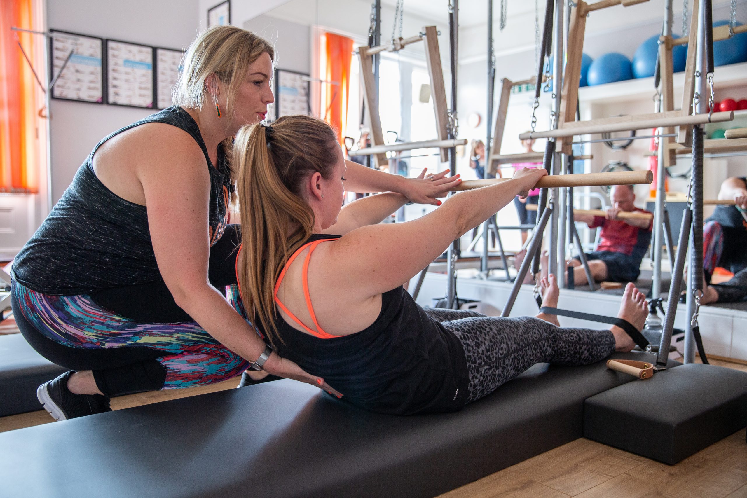 Pilates lady helping lady in pilates
